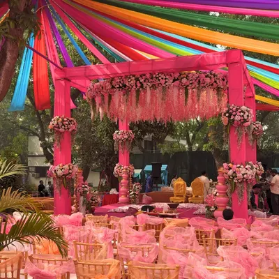For Jay and Jinal's Vidhi Mandap, we created a vibrant yet traditional setup. A canopy of rainbow-colored drapes radiated from the center, while the mandap itself was a beautiful structure in pink, adorned with delicate floral arrangements.