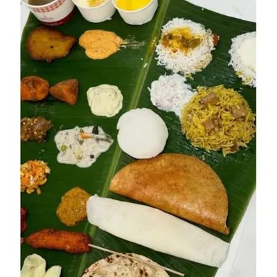 A complete South Indian vegetarian spread on a banana leaf. This meal features a variety of curries, rice dishes, dosa, vada, and sweets, offering a taste of everything.