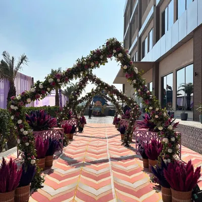 A grand floral walkway created for a Haldi carnival. We used arches of purple and white flowers with pampas grass accents to create a stunning entrance path for the guests.