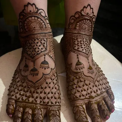 A full coverage foot mehendi featuring jhumka motifs and a delicate net pattern. This design provides a rich, traditional look for the bride's feet.