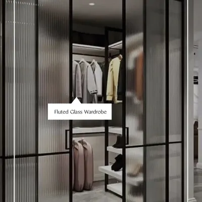 This walk-in closet features fluted glass sliding doors, offering a glimpse of the organized space within while adding a layer of texture and modern elegance. It is a perfect example of functional art.