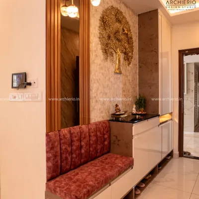 This luxurious foyer features a plush red velvet bench with integrated shoe storage, a gold tree-of-life mural, and elegant pendant lighting.