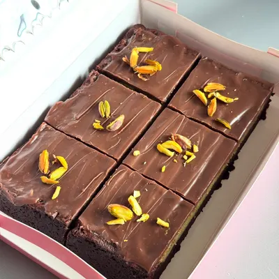 Here's a look inside a box of my special Kunafa Brownie Bars. I layer my best-selling fudgy brownies with a crunchy pistachio kunafa filling and top it all with smooth milk chocolate for a perfect blend of textures.