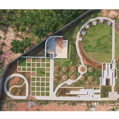An aerial view of a layout development in Bangalore, showcasing a central park area. Our master plans are anchored by significant green spaces that serve as the heart of the community.