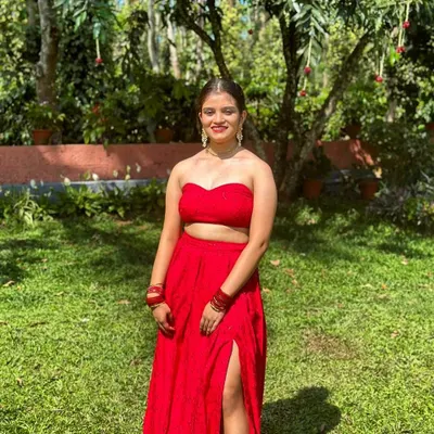 This bold red Indo-Western set features a modern sweetheart neck strapless top. It's paired with a matching high-waisted skirt with a thigh-high slit for a contemporary and confident look.
