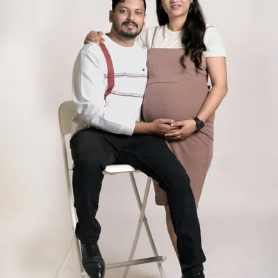 A simple and sweet studio portrait of an expecting couple. This classic pose beautifully highlights the baby bump and the supportive connection between the partners.
