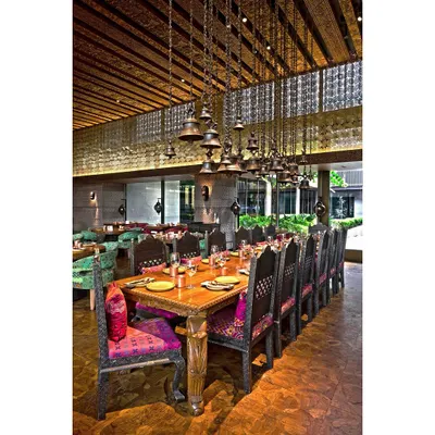 This wide shot of a restaurant's private dining area captures its grandeur and intricate design. We focused on the long wooden table and the dramatic overhead bell chandeliers to showcase the unique, traditional decor.