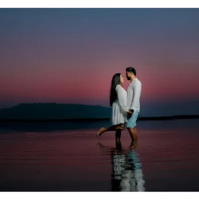 An intimate pre-wedding photo of a couple embracing in the water at dusk, with the deep colors of the sunset creating a romantic and serene atmosphere.