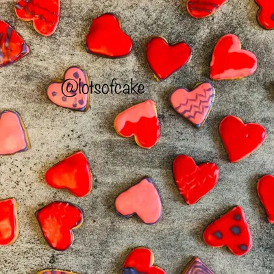 Choose your love wisely! A beautiful flat lay of my Valentine's Day cookies, each heart-shaped and decorated with unique red, pink, and purple royal icing designs.