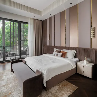 This bedroom feels like a true retreat. We designed it with layered textures, warm tones, and sleek metallic accents on the feature wall. The bespoke furniture and soft daylight from the balcony create a setting that’s both inviting and refined.