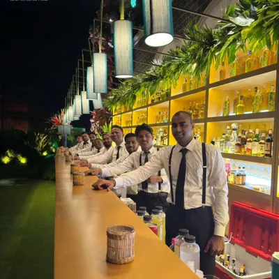 Our team of professional bartenders, lined up and ready for service at a large outdoor event. Dressed in sharp uniforms with suspenders, we are ready to bring both style and skill to your celebration.