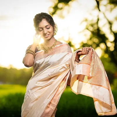 An elegant Onam look featuring our off-white and gold pattu saree paired with a navy blue embroidered blouse. This classic combination is available for rent for any festive occasion.