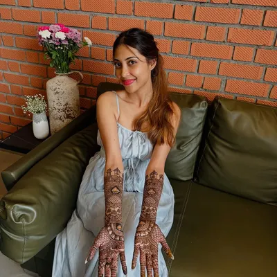 A happy bride proudly displaying her intricate full-arm mehndi. Her smile is the best reward for my detailed work.