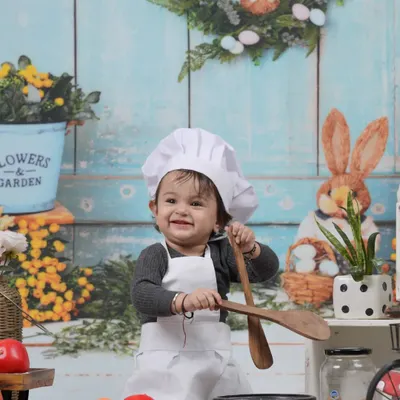 Our little chef, ready to cook up some fun. This adorable kitchen-themed studio setup is perfect for capturing your child's playful side.