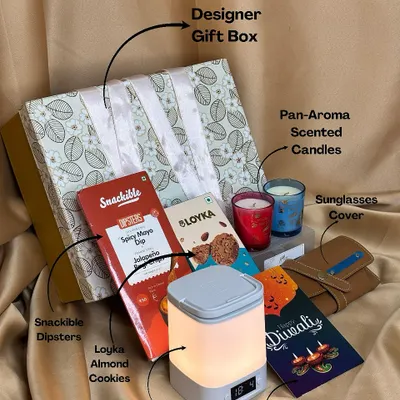 This hamper is the perfect blend of modern convenience and relaxation. It features a desk lamp with a clock and remote, pan-aroma scented candles, a sunglasses cover, and assorted snacks, all packed in a beautiful designer box.