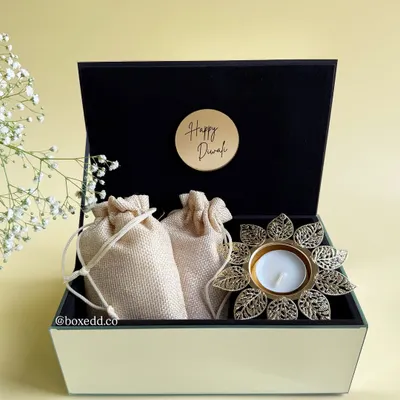 A classic Diwali gift box featuring a beautiful lotus diya and traditional potli bags, all housed in a luxurious glass and velvet hamper. It's a perfect blend of elegance and festive spirit for your corporate needs.