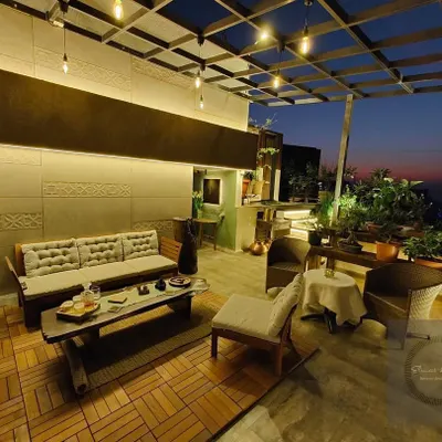 A terrace transformed into a stunning evening lounge. We used a wooden deck, comfortable low seating, and strings of Edison bulbs under a pergola to create a warm and inviting atmosphere perfect for private parties.