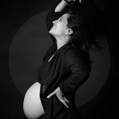 A joyful and dynamic black and white solo portrait. The movement in her hair and the genuine smile capture a feeling of freedom and happiness on the journey to motherhood.