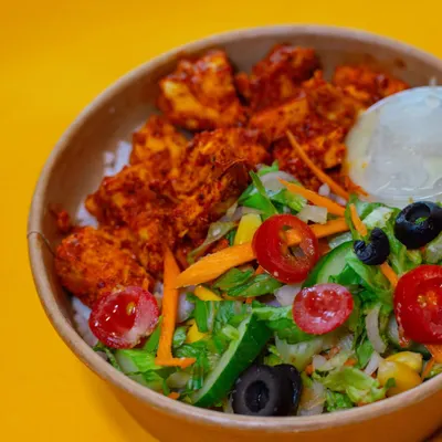 My Chicken Tikka Meal is a bestseller for a reason. It features tender, marinated chicken tikka pieces on a bed of rice, served with a fresh salad of tomatoes, cucumbers, and olives.