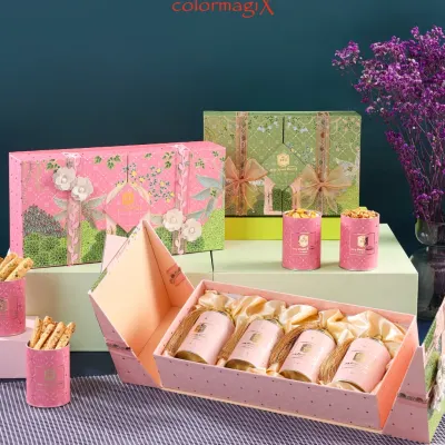 An elegant display of our luxury gift boxes in pink and green. This image highlights our intricate floral designs and the unique folding mechanism of the box, revealing a set of beautifully arranged smaller gift canisters inside.