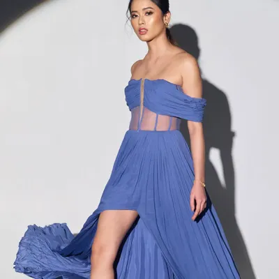 A full-length look from a fashion editorial. The makeup was designed to complement the flowing blue gown, with a focus on glowing skin and defined eyes that would stand out from a distance and draw attention to the model's expression.