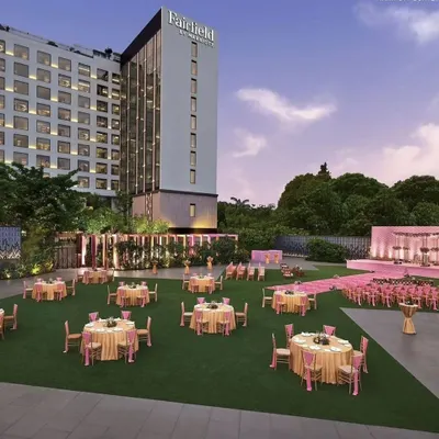 This image shows a grand lawn setup for a pastel-themed wedding. The pink stage and seating arrangements look stunning against the green lawn and the modern hotel backdrop, creating a picture-perfect scene.