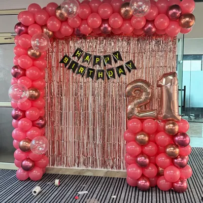 A complete 21st birthday setup in an office. The theme uses a popular pink and rose gold color scheme with a full balloon arch and number foils.