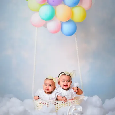 A whimsical and creative photoshoot for twin babies celebrating their six-month milestone. We designed a hot-air balloon theme with a basket, pastel balloons, and a cloudy backdrop for a magical and memorable shot.