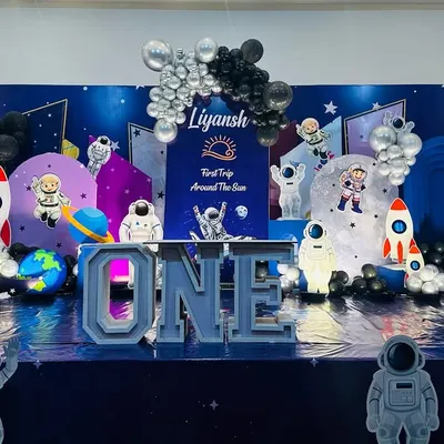 A spectacular outer space theme for a "First Trip Around The Sun." The entire stage is transformed into a galaxy with a star-studded floor, planet cutouts, astronaut figures, rockets, and a large "ONE" marquee table.