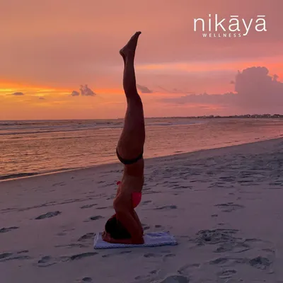 A client practices a supported headstand on the sand at dusk. Our beach yoga sessions are designed to build core strength and stability, using the natural environment to inspire focus and playfulness. This pose represents a milestone of dedication and trust in one's own practice.