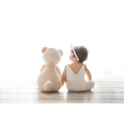 This is a perfect shot for a sitter session, which I offer for babies who can sit up on their own. Here, the baby shares a sweet moment with a teddy bear, looking back with a curious glance.