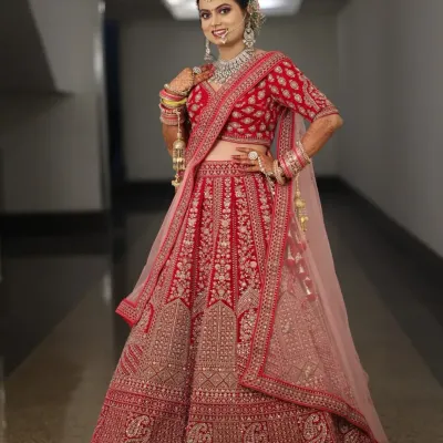 A full-length view of this gorgeous bride in her red and pink lehenga. The complete look, from the detailed makeup to the elegant hair and draping, creates a picture-perfect bridal moment.