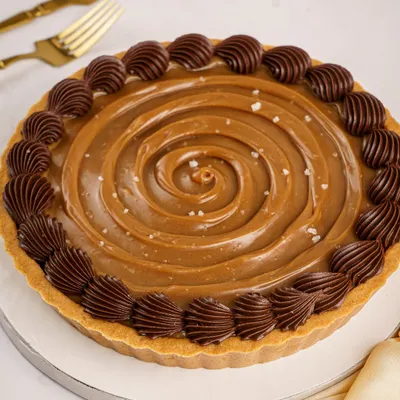 My Signature Chocolate Pudding Tart, finished with a perfect swirl of house-made caramel, a sprinkle of sea salt, and a decorative border of rich Belgian chocolate ganache.