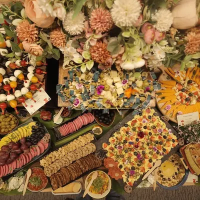 An abundant grazing table, artfully arranged to be the heart of the party. This spread features a wide variety of textures and flavors, from creamy cheeses to savory meats and sweet fruits.