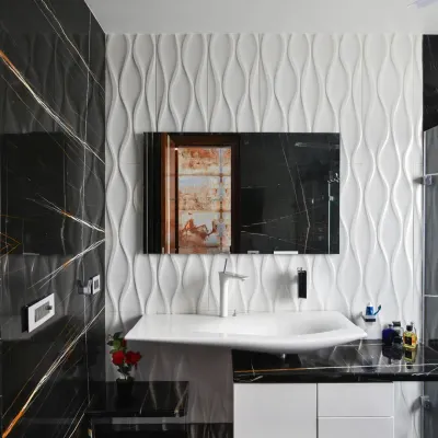 This bathroom in the Gupta Residence combines luxury and modernity with bold contrasts. Black tiles with golden veins define the space, while 3D white textured tiles add depth behind the minimalist vanity.