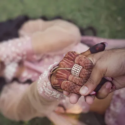 We believe that small details hold big memories. This artistic shot focuses on the bride's hand, adorned with beautiful henna and her wedding ring, held gently by her partner. It’s a creative and intimate style of wedding detail photography that adds a unique touch to your collection.