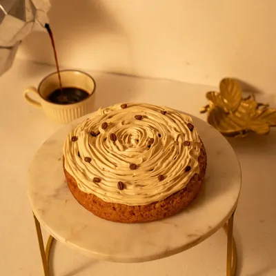 A coffee-infused cake on a marble stand, with espresso being poured in the background. This action shot adds a dynamic element and tells the story of the cake's flavor profile.
