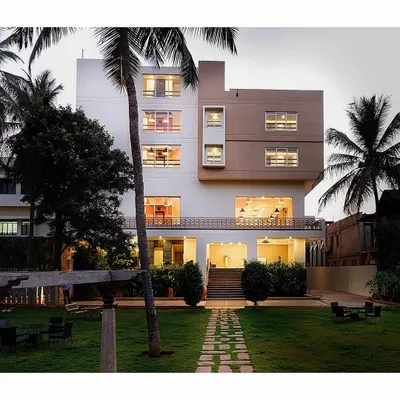 The entrance to this hotel is defined by a classic and elegant landscape design. A manicured lawn, flanked by tall palm trees and a central stone pathway, creates an inviting and upscale welcome for guests.