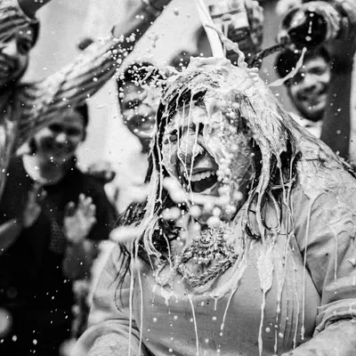 The Haldi ceremony in full swing. This shot captures the peak of the fun, a moment of pure, uninhibited joy as the bride is showered with milk and love by her friends and family.