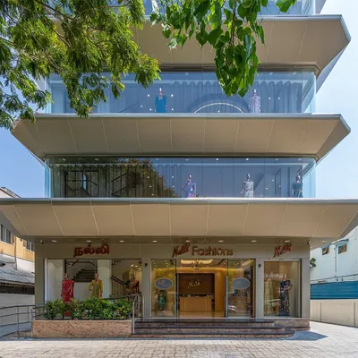 The completed facade of the Nalli flagship store in Anna Nagar, Chennai. The design features deep, ship-hulk-like overhangs that provide shade, create a dynamic visual, and nod to the Art Deco style of the original Nalli store.