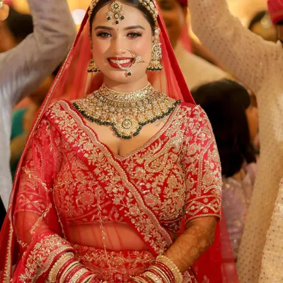 The pure joy of a bride on her wedding day. This radiant smile says it all. We went for a classic red lehenga look with a bright lip and defined eyes, ensuring she looked and felt absolutely unforgettable.