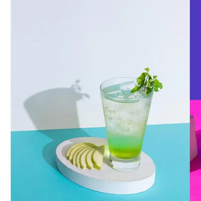 A refreshing green apple mocktail, styled with sharp shadows and bold color blocks for a modern, graphic look.