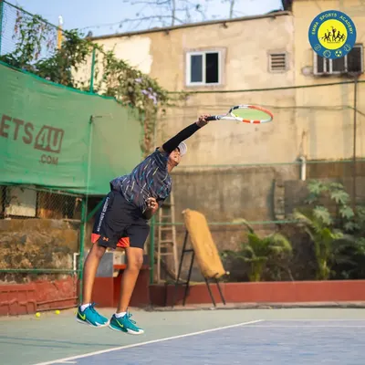 A player is captured at the peak of their serve, demonstrating explosive power and perfect form. This is the kind of technique we help develop on our courts.