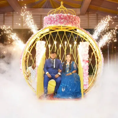 A grand reception entrance designed to look like a scene from a movie, with the couple seated in a carriage amidst smoke and sparklers.