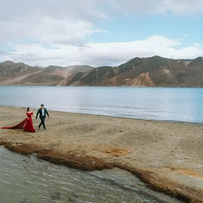 A walk to remember along the serene banks of Pangong Lake in Ladakh. The vast landscape emphasizes the couple's journey together.