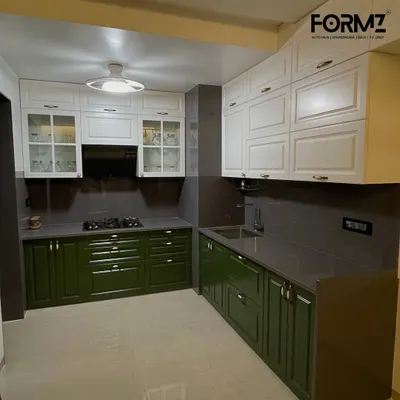 A beautiful L-shaped kitchen combining classic olive green shaker-style base cabinets with clean white overhead units. The glass-fronted upper cabinets and traditional handles add a touch of timeless elegance.