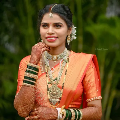 A professional portrait of a radiant Maharashtrian bride. I draped her orange wedding saree to highlight the intricate work on the pallu and ensure a perfect, photo-ready finish.