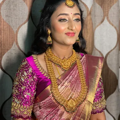 Bride Vidya's reception look is all about modern glamour. She wears a beautiful magenta Kanchipuram saree with a heavily embroidered blouse, which I paired with soft, open curls and glowing makeup.