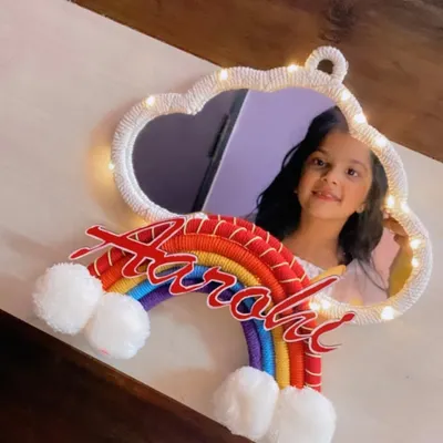 A personalized mirror is a wonderful gift. This cloud-shaped mirror for 'Aarohi' is framed with white macrame cord and includes fairy lights and a colorful rainbow name accent.