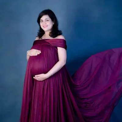 The magic of a fabric toss. This off-the-shoulder maternity gown in a rich magenta color creates a beautiful, dynamic shape, making for a truly show-stopping portrait.
